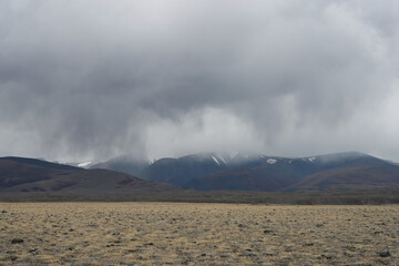 Thunderclouds and rain coming from snowy mountains over the steppe