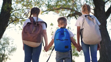 A group of children are standing in the forest with backpacks on their backs. Backpack nature hiking concept. Schoolchildren with backpacks in the park. Children and park schoolchildren in the. - Powered by Adobe