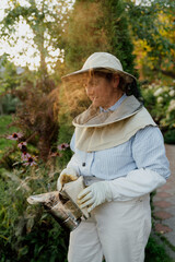 Female beekeeper holding bee smoker