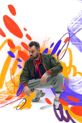 Creative artwork. Male model crouching in casual streetwear with colorful graffiti inspired...