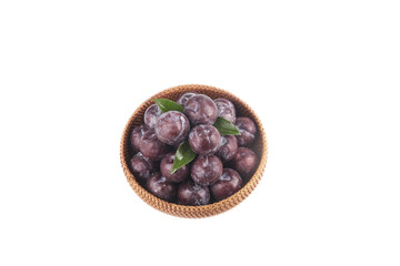 Fresh Purple Plums in Wicker Basket with Green Leaves on White Background