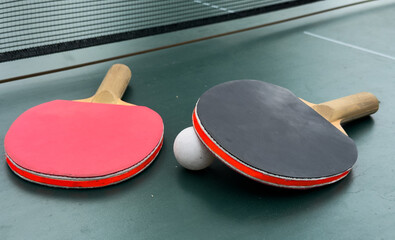Two ping pong rackets and ball on table