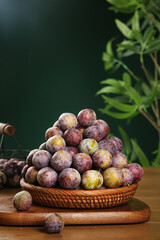 Fresh Picked Sichuan Plums with Red and Yellow Flesh in Wicker Basket on Wood Table