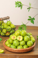 Fresh Green Plums in Wicker Basket on Wooden Table with Natural Vine Decoration