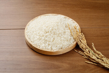 Fresh White Rice in Wooden Bowl with Wheat Stalks on Wood Background
