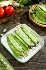 Fresh green pea pods with beans and vegetables on rustic wooden table - healthy organic ingredients