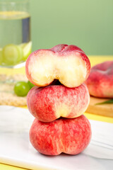 Fresh Red Shaanxi Flat Bottom Peaches Stacked with Cut Half Showing Interior on White Plate