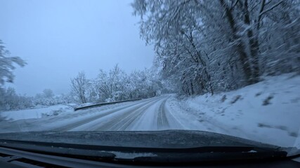 Vehicle driving on snowy road through winter forest. Winding snowy road traversing snow-covered forest landscape, capturing scenic winter journey through tranquil wilderness