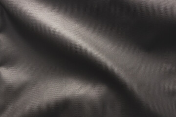 A close-up, top-down view of a dark gray or black fabric, showcasing its durable and textured surface. The material appears to be a heavy-duty synthetic textile.