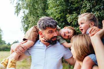 Joyful parents playing with children together outdoors showing love and family bonding