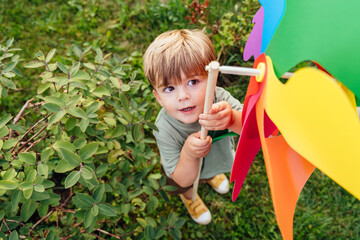 Toddler playing with rainbow pinwheel in summer garden