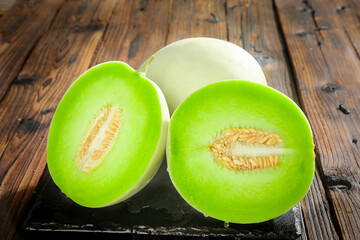 Fresh Jade Melon Halves with Green Flesh on Rustic Wood Background - Shandong Fruit