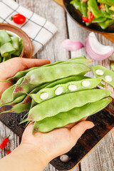 Fresh Green Pea Pods with White Beans in Hands - Healthy Cooking Ingredients on Wooden Kitchen Table