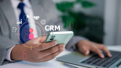Business Person Holding Smartphone with CRM Icons Digital Overlay for Customer Relationship...
