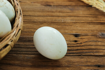 Fresh Duck Eggs with Speckled Shells in Wicker Basket on Rustic Wooden Farmhouse Table