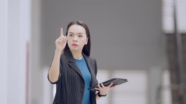 Empowered business leader in office setting holding tablet and guiding forward with stylus, embodying confidence in leadership and vision.