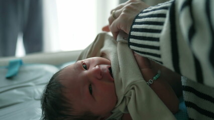 Mother tenderly caring for her newborn baby, dressing the baby in clothing, capturing an intimate moment of maternal care and love in a softly lit indoor environment-SD 480p