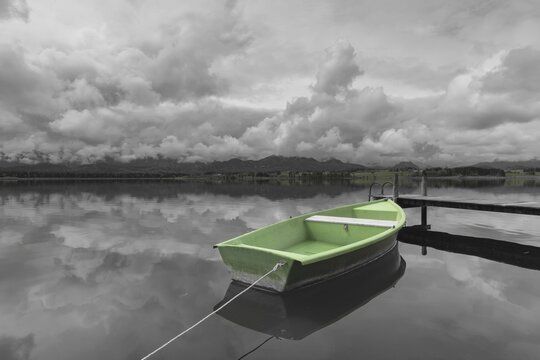 Storm clouds at sunset, a green rowing boat lashed to the wooden jetty, Hopfensee, Hopfen am See, near F&uuml;ssen, Ostallg&auml;u, Allg&auml;u, Bavaria, Germany