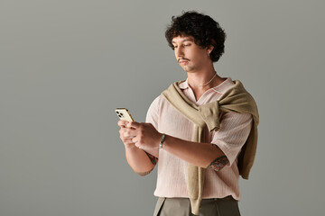 Stylish young man engaged in texting while showcasing modern fashion sense indoors