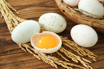 Fresh White Eggs with Golden Yolk in Wicker Basket on Wooden Background with Wheat Stalks