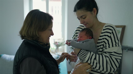 Mother handing a newborn baby to the grandmother, capturing a tender moment of family bonding and love in a softly lit indoor setting-SD 480p