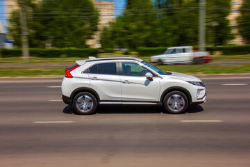 Dynamic white SUV speeding down a city street on a sunny day