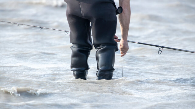 Angler in Watthose beim Fischen &ndash; Freizeitfischer im Wasser mit Angelrute, Symbol f&uuml;r Geduld, Ruhe und Naturverbundenheit