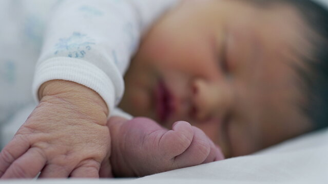 Newborn baby sleeping with hand and foot in focus, emphasizing the delicate and gentle nature of early infancy in a cozy setting-SD 480p