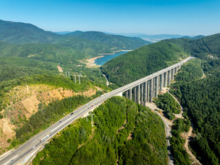 Aerial view of a highway viaduct bridge spanning a lush green mountain valley. Modern transportation infrastructure, engineering. Road trip travel