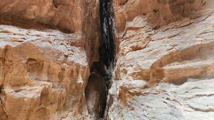 Massive rock formations rise dramatically against a cloudy sky in AlUla, Saudi Arabia. These sandstone cliffs display rugged textures and layered hues of ochre and brown. The impressive geological