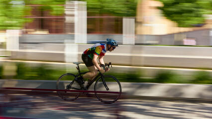 Cyclist speeding on road bike in motion blur with strong focus and determined emotion. Concept of...