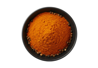 黒いボウルに入った鮮やかなオレンジ色のスパイスパウダーと黒胡椒粒のトップビュー