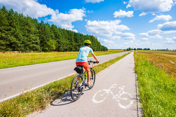 Female tourist biker riding on beautiful cycling road, Roztocze region, Poland