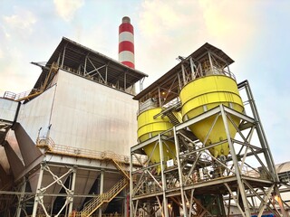 Industrial landscape showcasing a modern power plant with tanks and a striped chimney demonstrating...