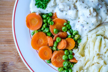 Cod Fillet Fish With Mashed Potatoes Carrots And Peas In A Pasley Sauce