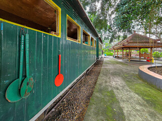 Green Vintage Train Car with Wooden Spoons Decor in Lush Tropical Setting