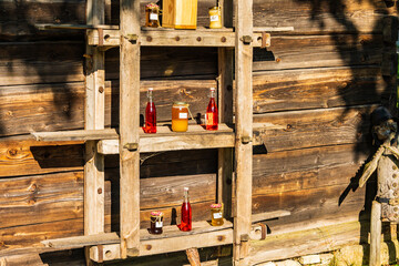 Bottles and jars with homemade jam and honey on wooden shelf of a shop in Guciow village, Roztocze...