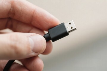 Close Up of Hand Holding a Black USB Cable Connector