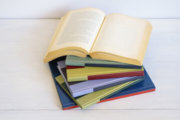 Stack of different colorful books on white rustic table.  Copy space