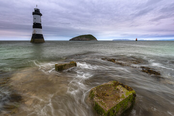 Fototapeta premium Trwyn Du Lighthouse oder Penmon Point Lighthouse auf der Insel Anglesey an der Küste von Wales bei Sonnenaufgang