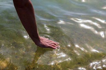 Man’s hand touching the sea water close-up