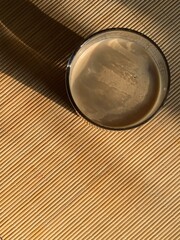Glass of morning coffee on bamboo wood table with sun light and shadow