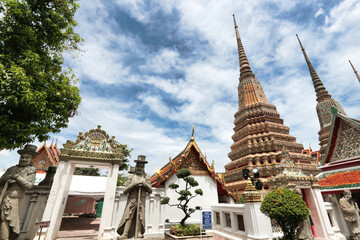 Fototapeta premium Guarding statues and chedi at Wat Pho - Ornate chedi and guardian statues with a Western influence, a blend of cultures at the famous Wat Pho temple in Bangkok.