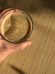 Glass of morning coffee on bamboo wood table with sun light and shadow