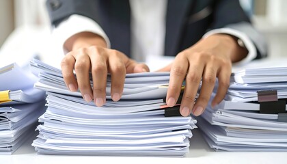 Hands sorting through a large stack of papers on a desk