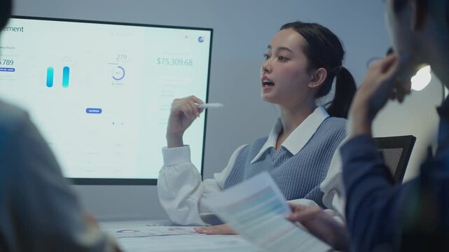 Modern office scene with an Asian businesswoman explaining financial charts and advice to her team. - Powered by Adobe
