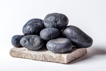 Pile of dark gray smooth stones on a rough textured stone slab r