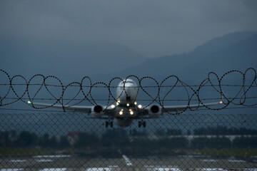 Airplane taking off from runway with barbed wire in the background. Airplane with barbed wire on...