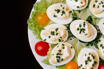 Stuffed eggs with mayonnaise and herbs on plate. Traditional appetizer closeup. Fresh homemade dish. Festive party food detail. Healthy protein meal with garnish.