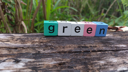 Colorful wooden block letters spell out the word green against a natural backdrop, freshness and...